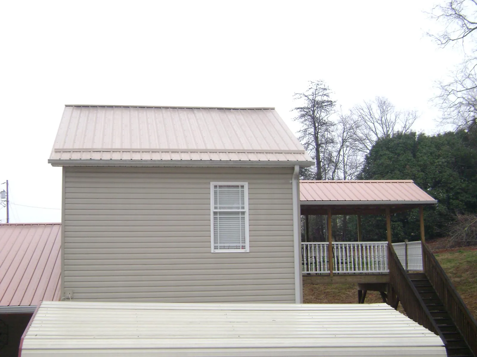 Tan metal roofs on a two story addition and attached porch, from a Roof Replacement job in Woodbridge